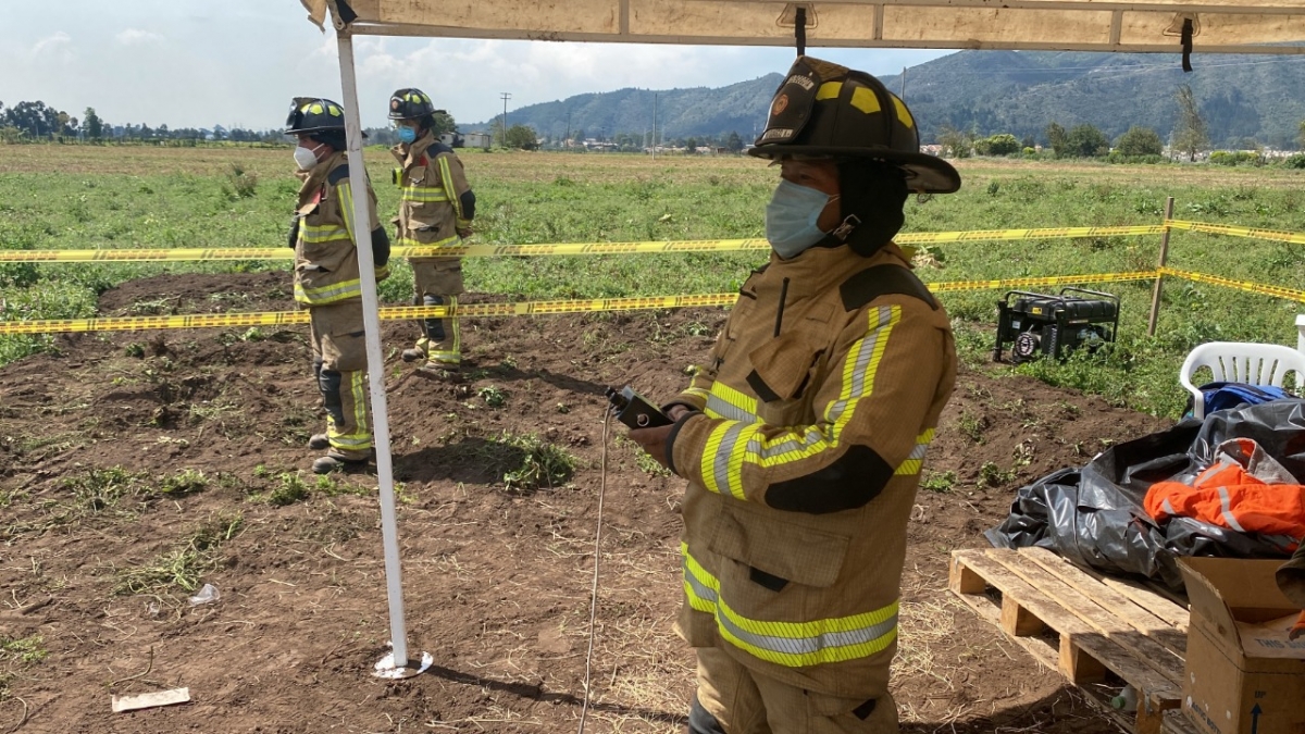 Tres Bomberos de pie observando la quema de pólvora 